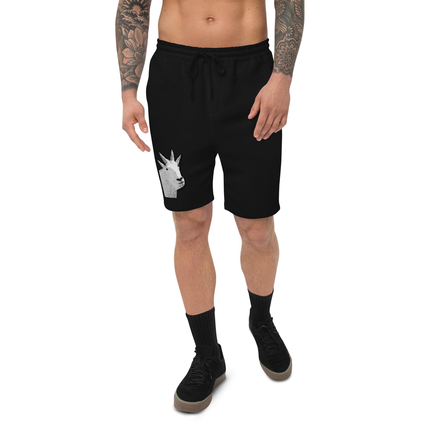 A male model with arm tattoos wearing a pair of black fleece shorts with a funny mountain goat design on the right leg and a pair of black shoes.