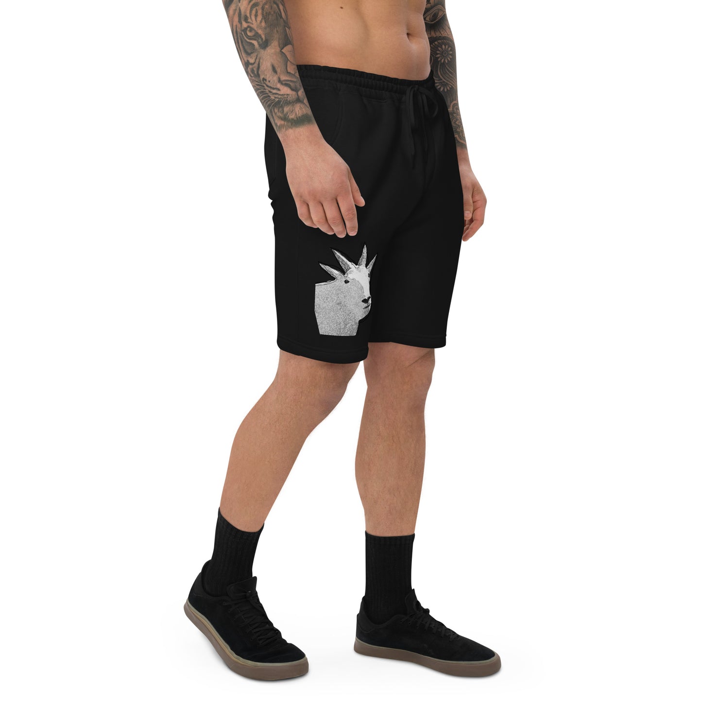 A male model with arm tattoos wearing a pair of black fleece shorts with a funny mountain goat design on the right leg and a pair of black shoes.