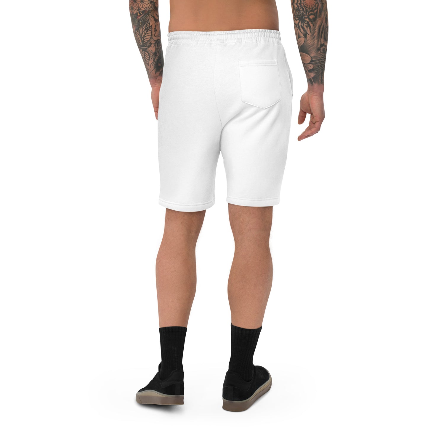 A male model with arm tattoos wearing a pair of white fleece shorts with a funny mountain goat design on the right leg and a pair of black shoes.