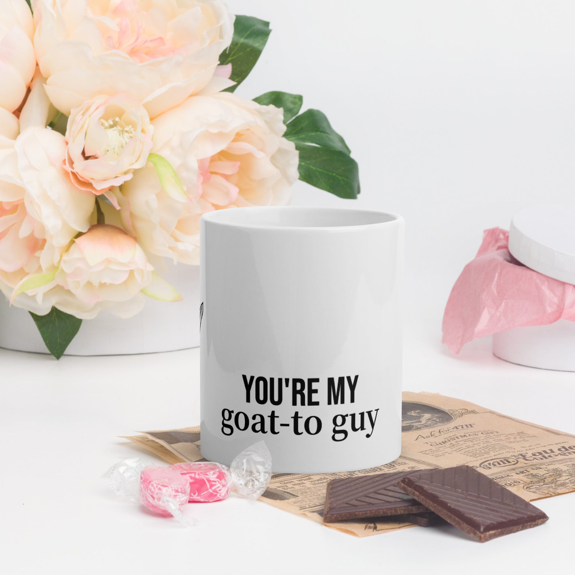 A white glossy mug that has a funny mountain goat design, the quote "You're My Goat-To Guy", and the logo North American Mountain Goat Appreciation Club.