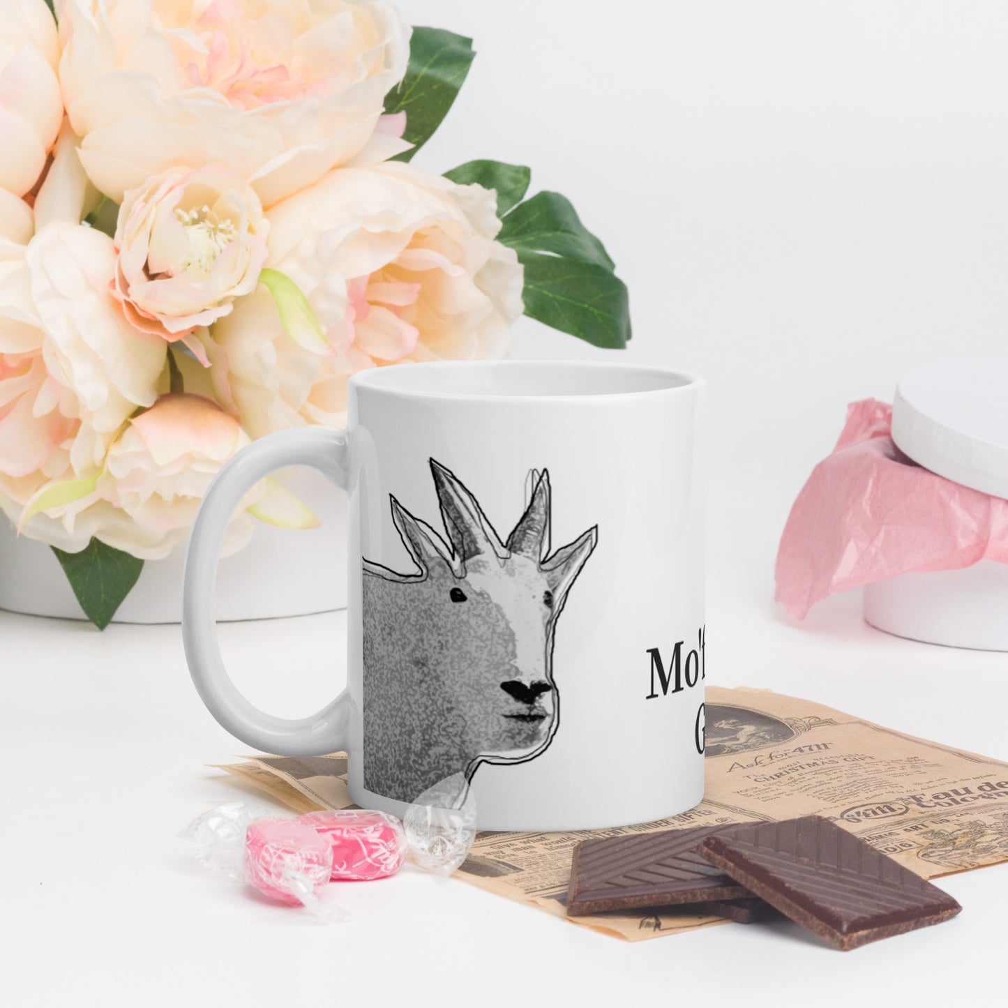 A white glossy mug that has a funny mountain goat design, the quote "Mo'f*ckin' Goat", and the logo North American Mountain Goat Appreciation Club.