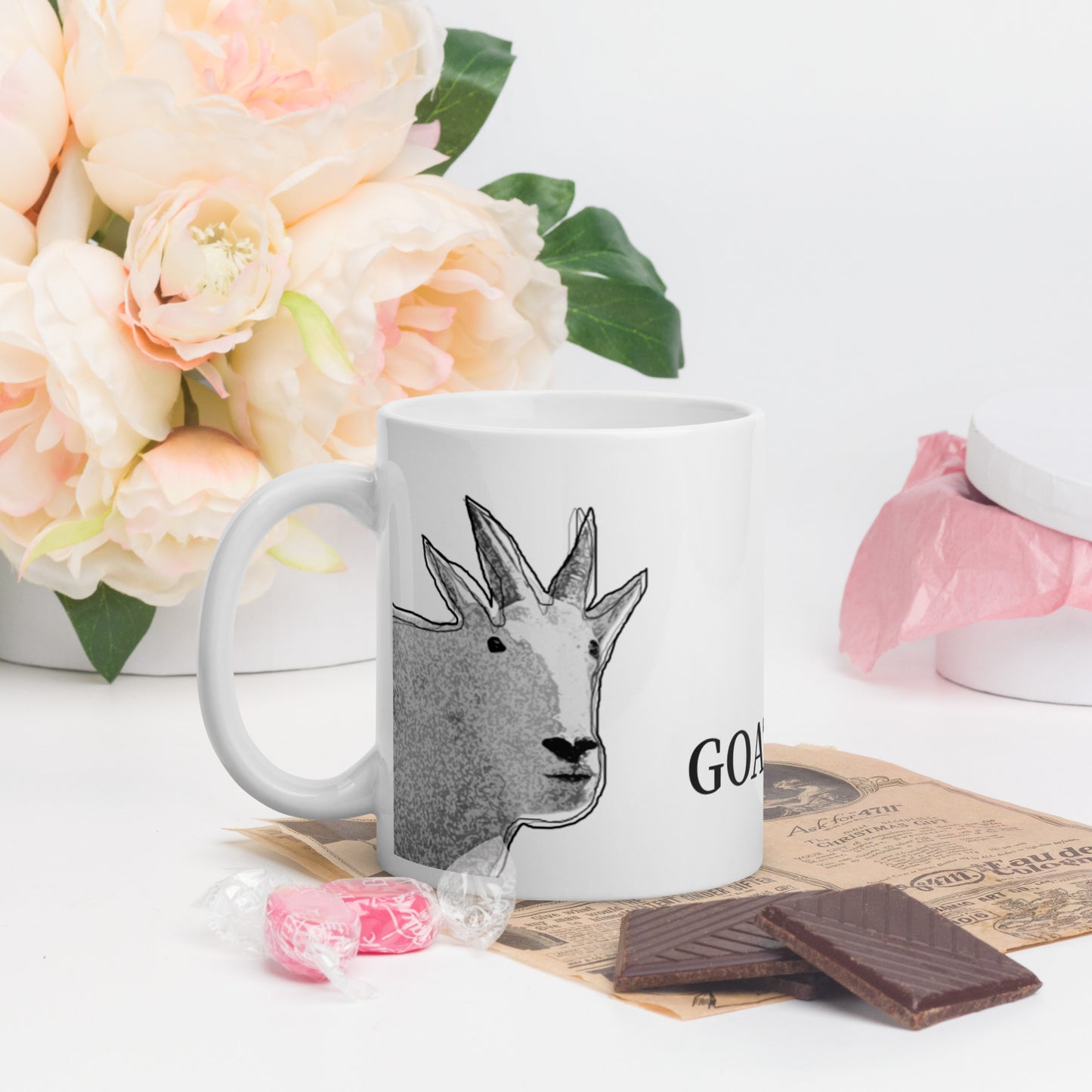 A white glossy mug that has a funny mountain goat design, the quote "GOATCHA.", and the logo North American Mountain Goat Appreciation Club.