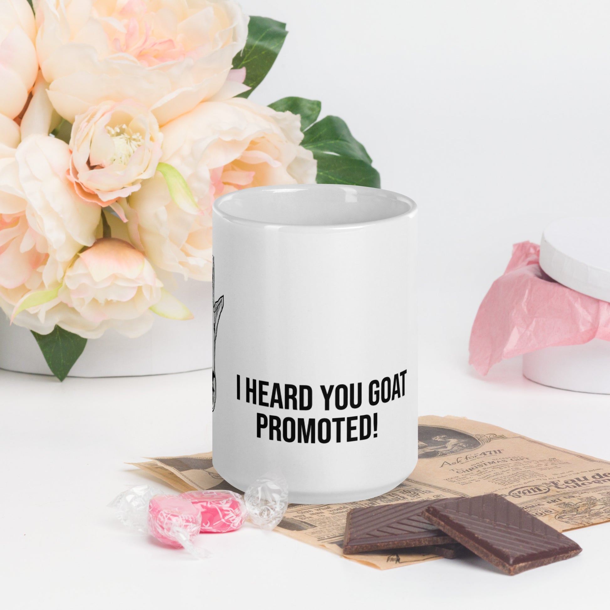 A white glossy mug that has a funny mountain goat design, the quote "I Heard You Goat Promoted", and the logo North American Mountain Goat Appreciation Club.