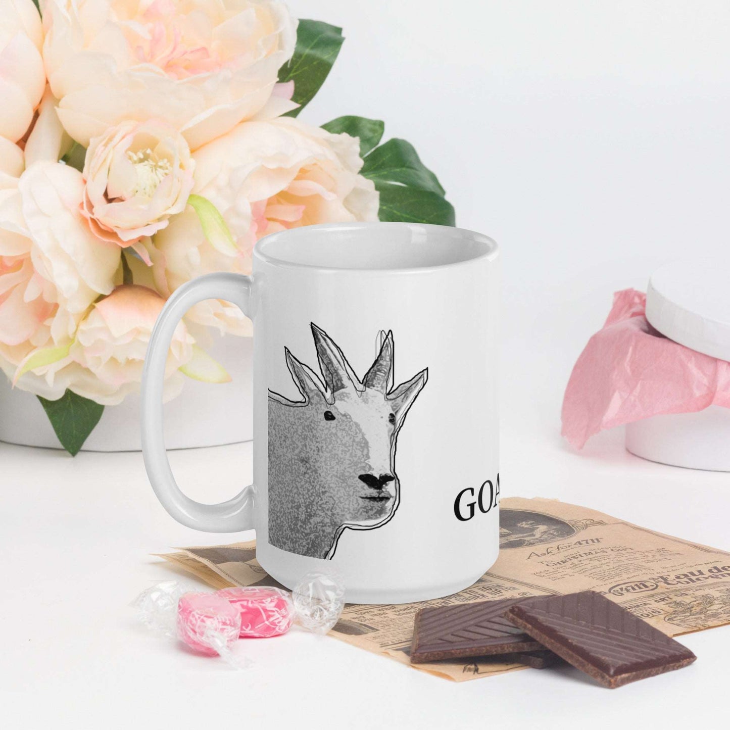 A white glossy mug that has a funny mountain goat design, the quote "GOATCHA.", and the logo North American Mountain Goat Appreciation Club.