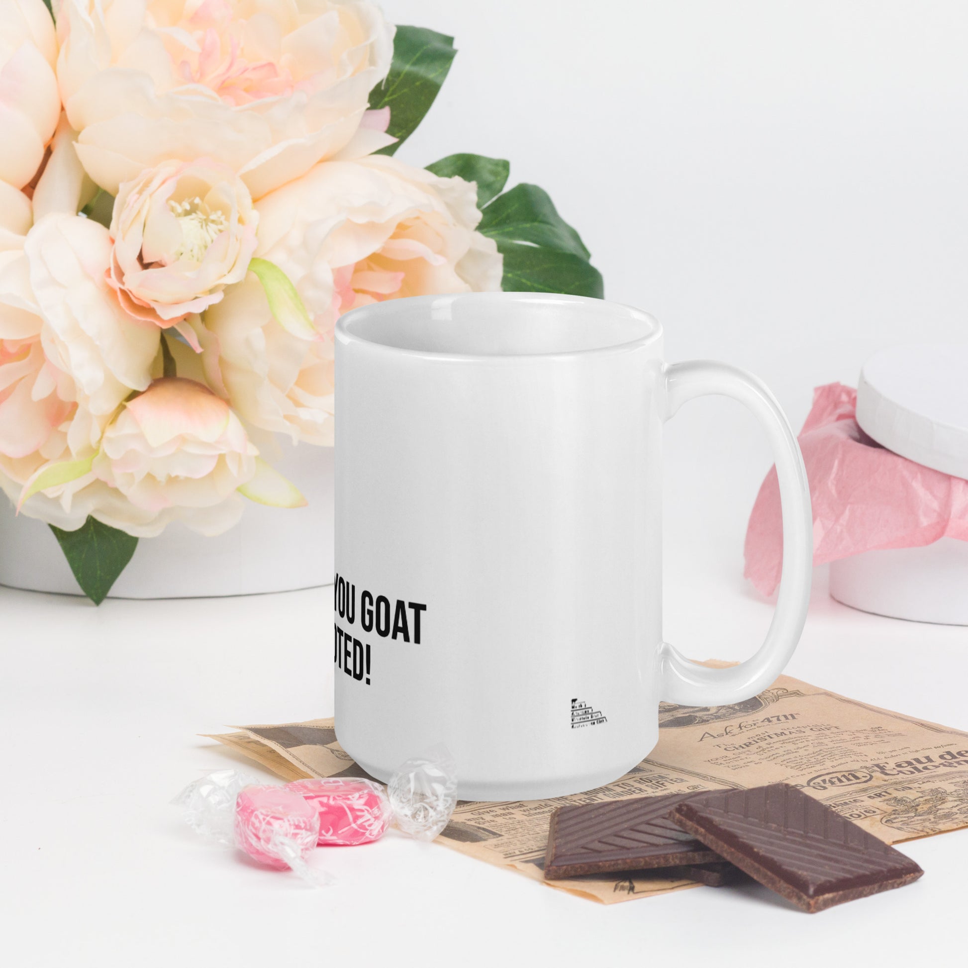 A white glossy mug that has a funny mountain goat design, the quote "I Heard You Goat Promoted", and the logo North American Mountain Goat Appreciation Club.